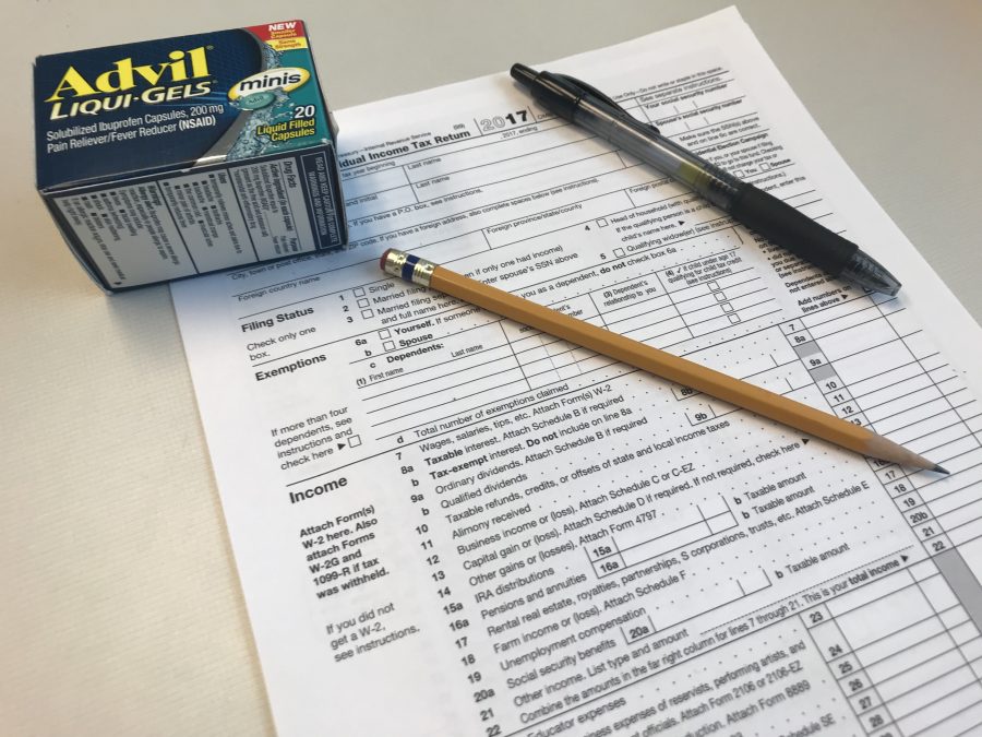 tax form with a pencil, a pen and a box of Advil