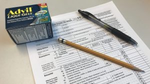 tax form with a pencil, a pen and a box of Advil