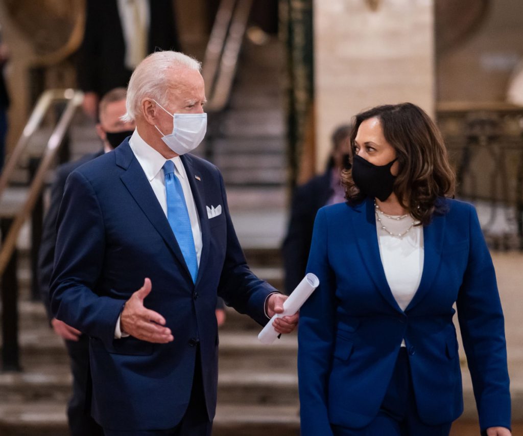 President Biden and Vice President Kamala Harris wear masks while facing each other.