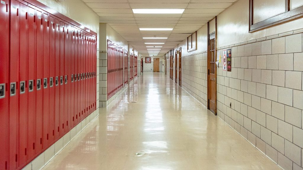 school hallway lined with red lockers and white brick