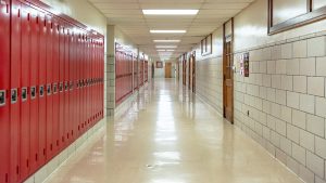 school hallway lined with red lockers and white brick
