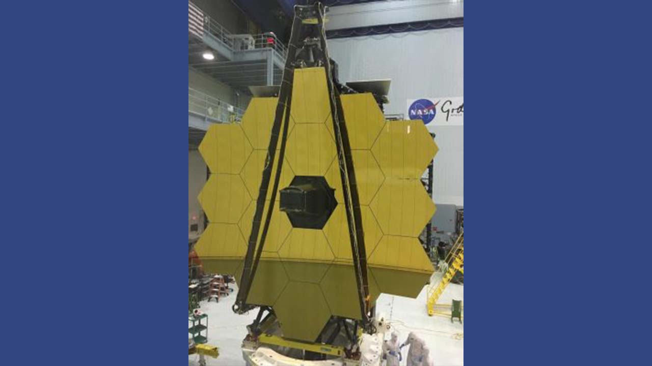 NASA scientists next to the large James Webb Space Telescope.