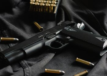 A black revolver on black cloth, with ammunition