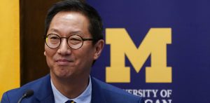 Santa Ono stands in front of a University of Michigan sign