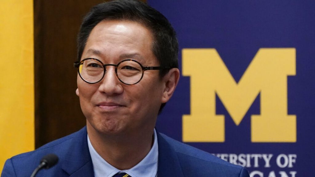 Santa Ono stands in front of a University of Michigan sign