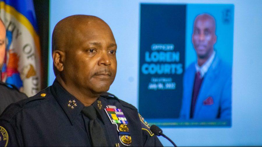 Detroit Police Chief speaks at a podium with a photo of Officer Loren Courts behind him.