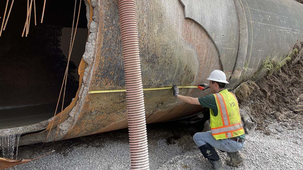 A worker inspects a pipe after a GLWA water main break