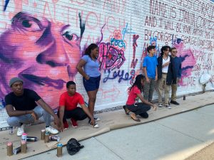 mural in progress with young people standing in front of it