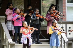 eight children play violins on the front steps of a Woodbridge home