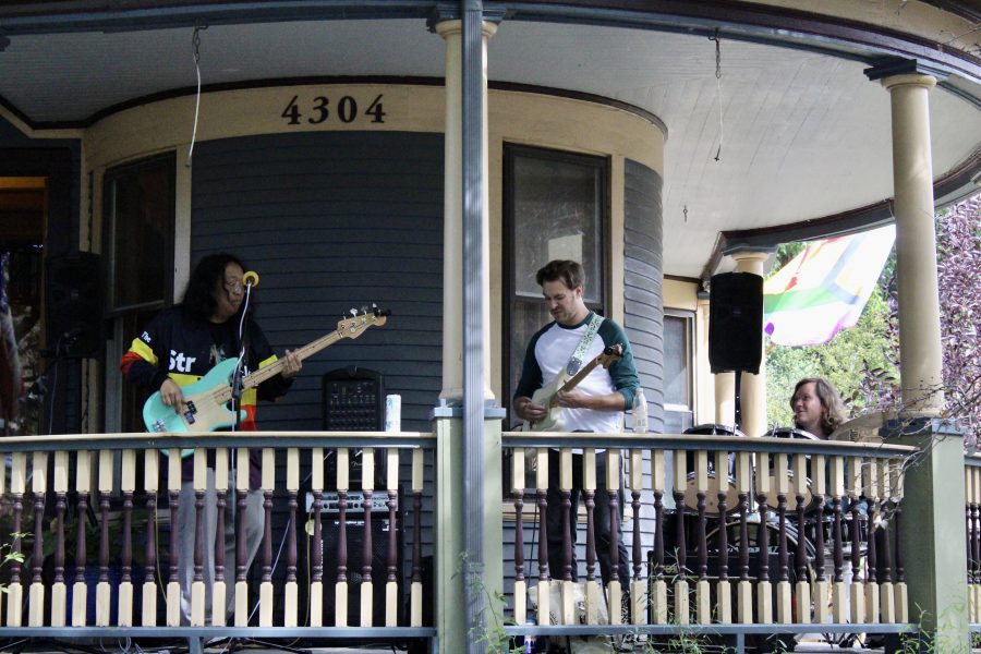 A bassist, an electric guitarist and a drummer perform on a Woodbridge porch