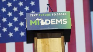 podium that reads "MI Dems" in front of an American flag