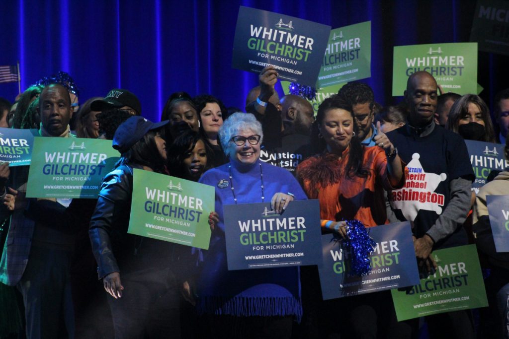 supporters hold "Whitmer/Gilchrist" campaign signs at the election night watch party in Detroit