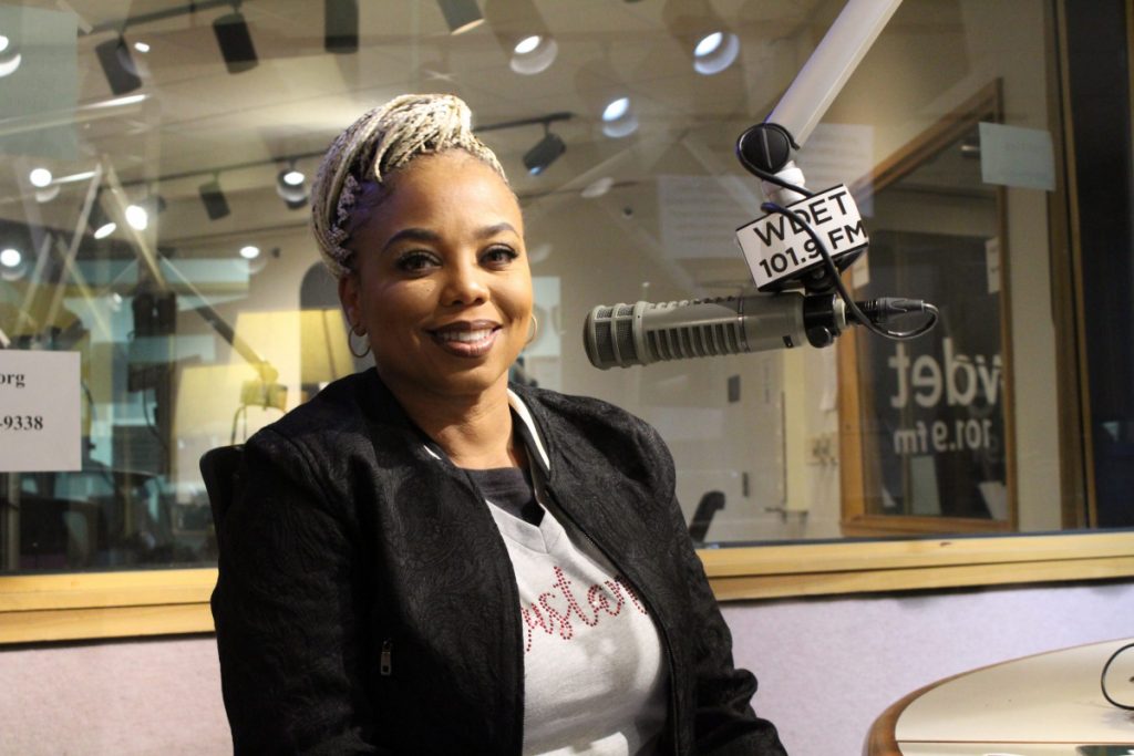 Jemele Hill smiles in front of a microphone in the WDET studios