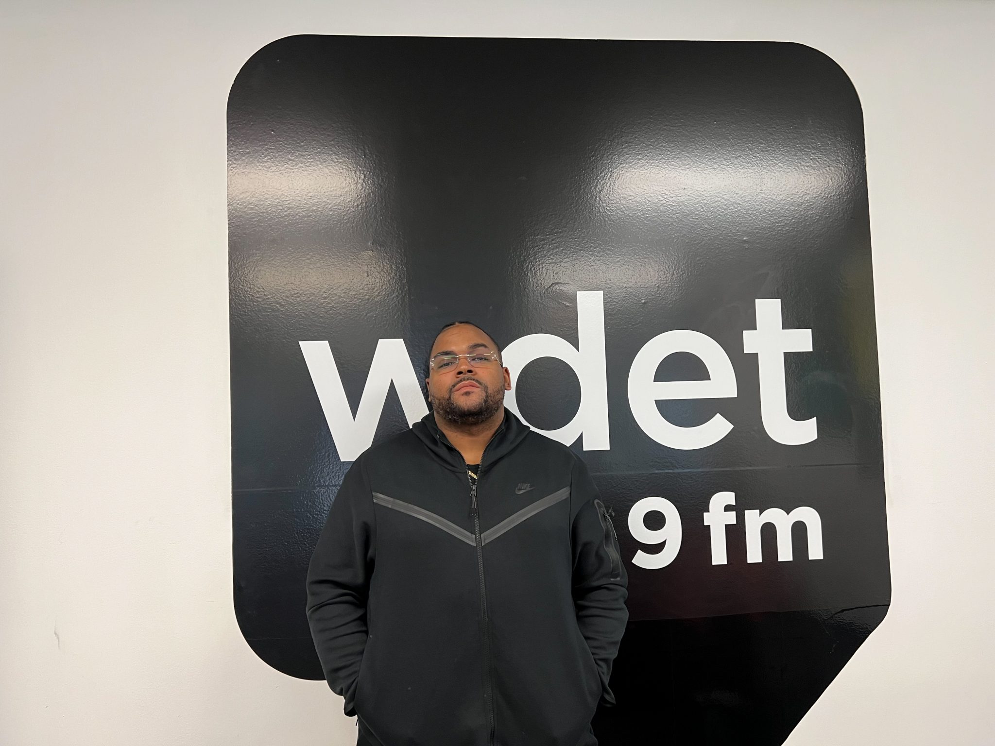 Young RJ poses in front of the WDET sign