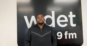 Young RJ poses in front of the WDET sign