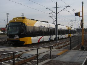 a yellow and white light rail train sits in a station