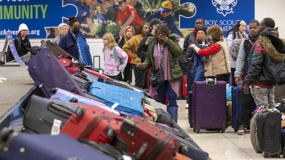 Travelers search through mountains of luggage at the baggage claim at Chicago Midway International Airport, Monday, Dec. 26, 2022, in Chicago.