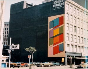 historic image of David Rubello's "Color Cubes" mural on the side of a building in Detroit. The mural features a geometric illustration of twelve vibrantly colored cubes overlapping one another.