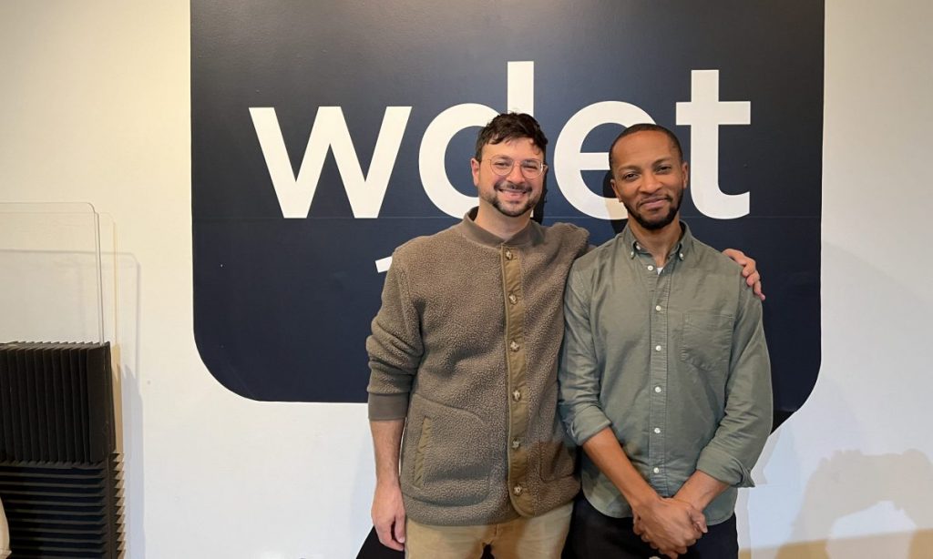 Michael Malis and Marcus Elliot smile in front of the WDET logo