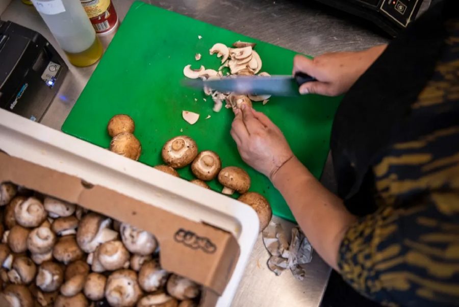 someone slices mushrooms on a green cutting board