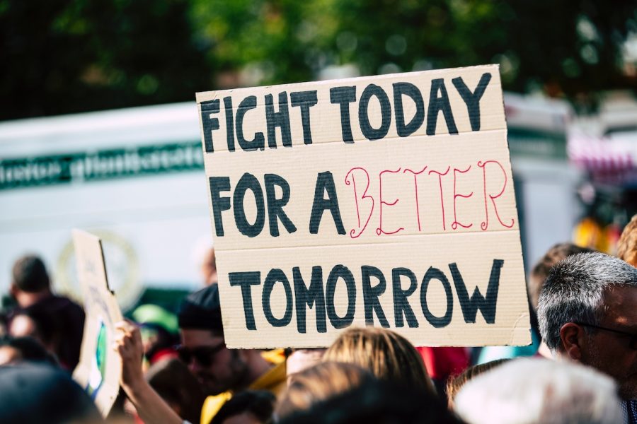 cardboard sign that reads "fight today for a better tomorrow" held up in a crowd of people
