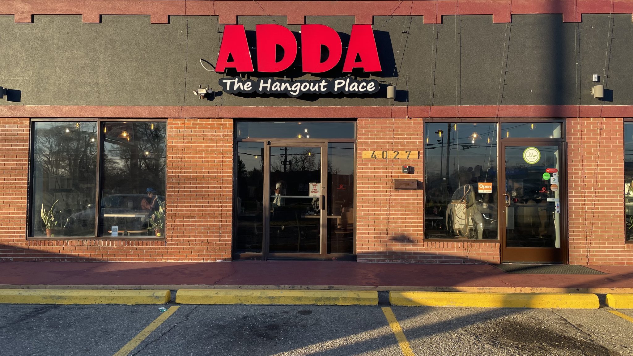 exterior of a brick building with a sign that reads "Adda: The Hangout Place"