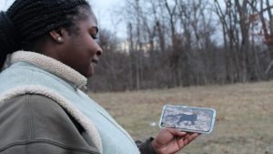 Researcher looks at an image of a cat holding a rabbit in its mouth. The image was taken in a Detroit park and is part of an ongoing research project on urban wildlife.