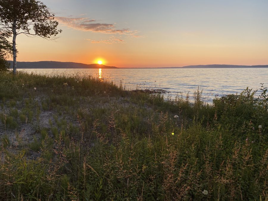 the sun sets over a lake with a grassy shore in northern Michigan