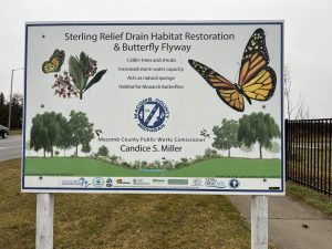 Sign with illustrations of trees and butterflies reads, "Sterling Relief Drain Habitat Restoration and Butterfly Flyway"