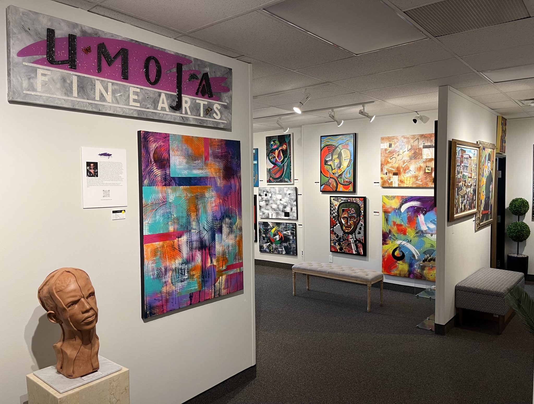 interior of an art gallery with colorful paintings and sculptures against white walls