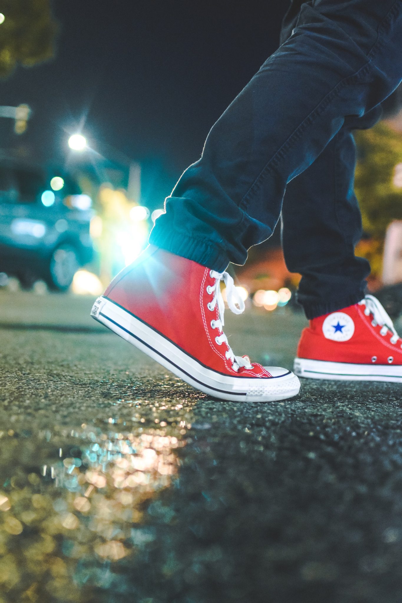 red sneakers walking on a rainy street at night