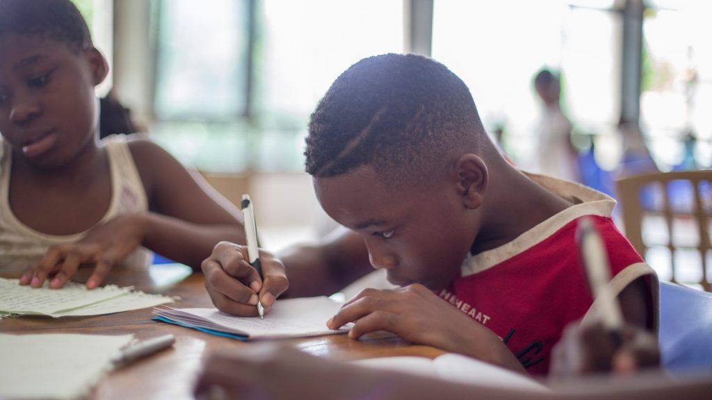 young Black boy writing in a classroom