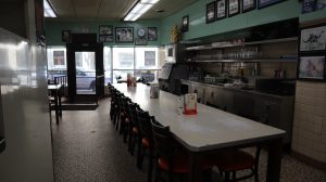 Interior of Lafayette Coney Island with a long gray dining table and sea foam green painted walls
