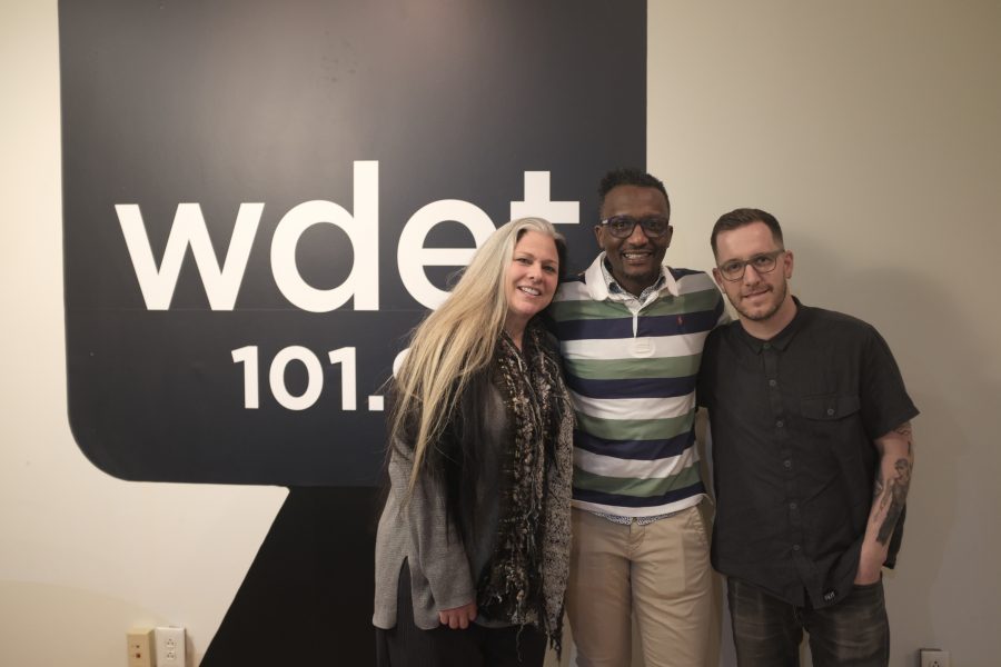 Hamissi Mamba of Baobob Fare stands with Ann Delisi and James Rigato in the lobby of WDET, radio station.