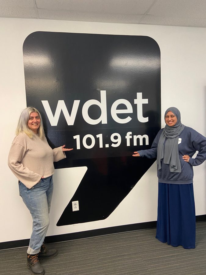 Eater Detroit editor Serena Maria Daniels and WDET reporter Nargis Rahman post in front of a WDET logo.
