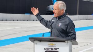 Bud Denker stands at a Detroit Grand Prix podium at a press conference