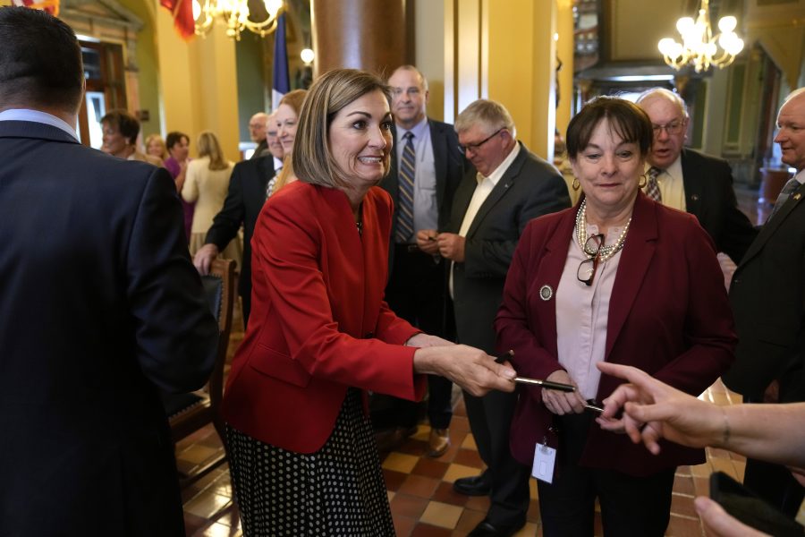 Iowa Gov. Kim Reynolds passes out pens after signing a property tax cut bill, Thursday, May 4, 2023, at the Statehouse in Des Moines, Iowa.