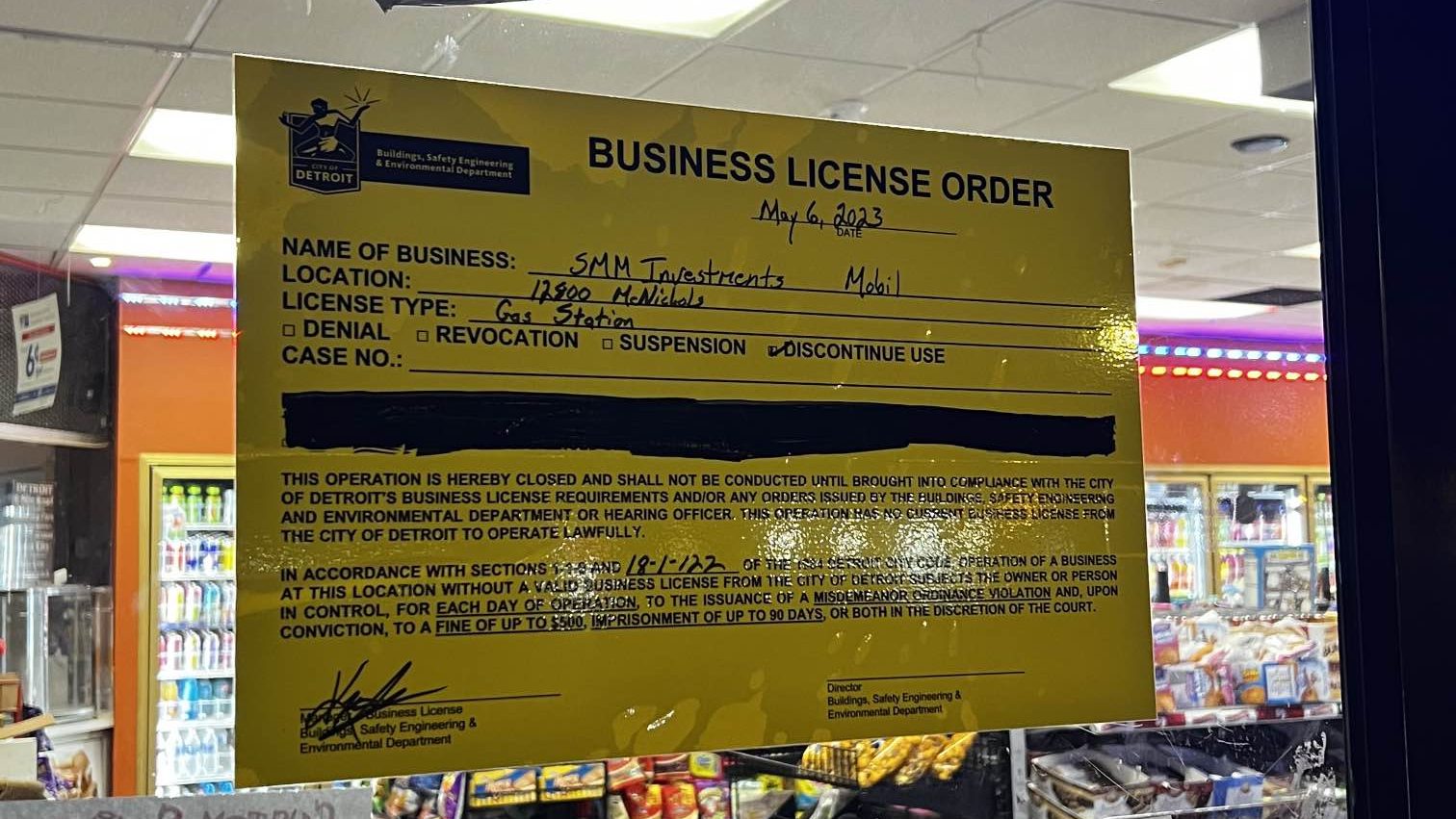 A sign displayed showing a violation by a gas station operating without a valid business license.