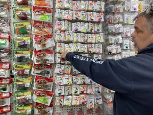 A man points to different colorful fishing lures
