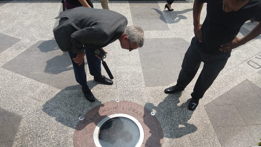 Pat Batcheller and Ken Coleman observe the "point of origin" in Campus Martius, a white stone ⁠encased underneath a glassy porthole.