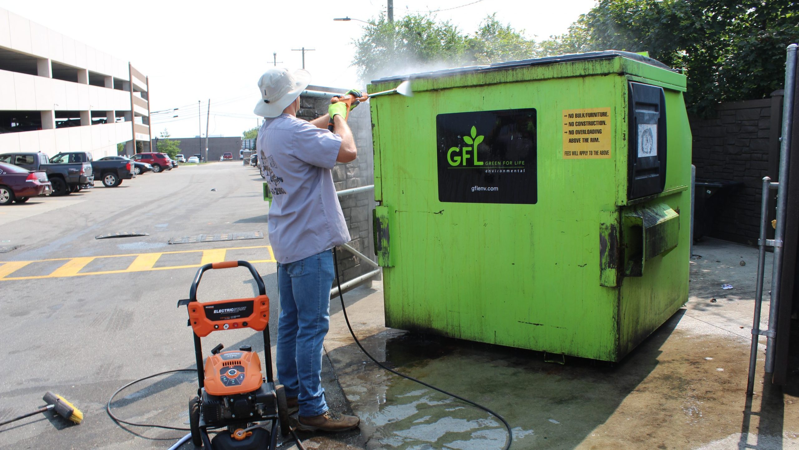 A contractor power washes a dumpster in Dearborn.
