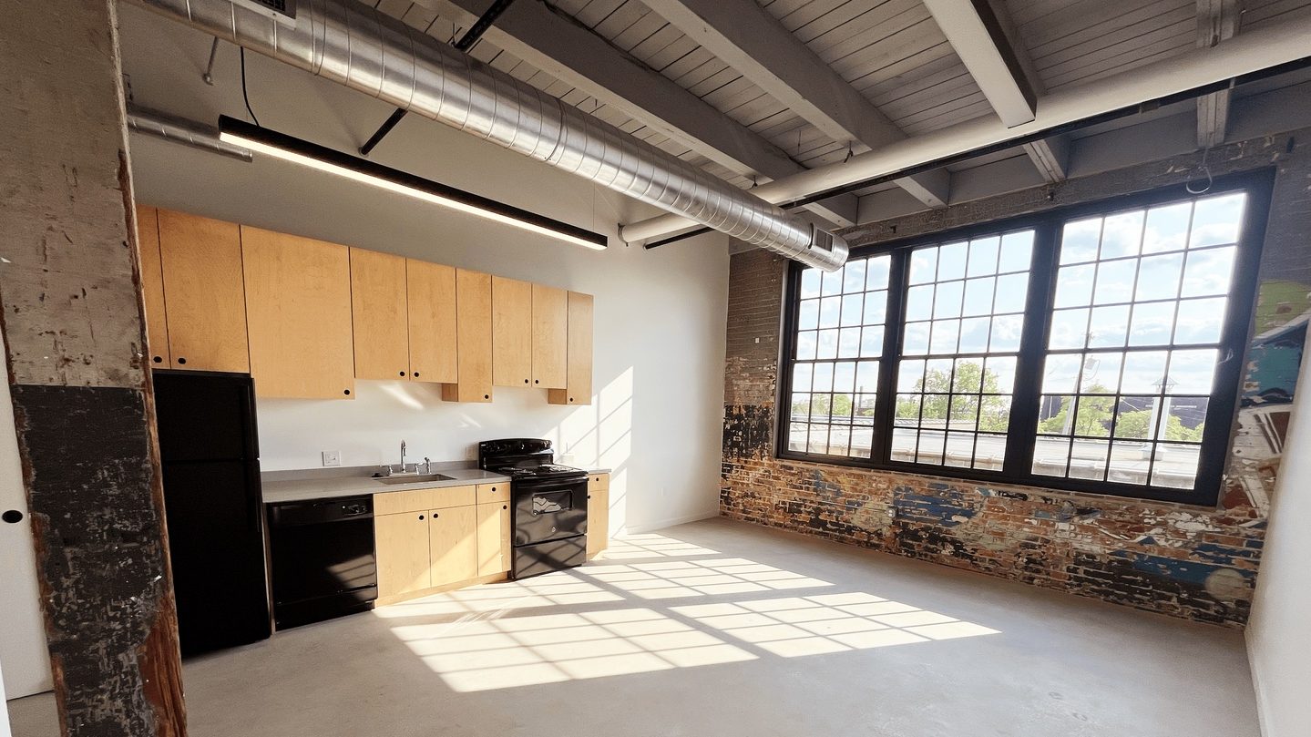 Interior of a Dreamtroit appartment, with a kitchen, a large window and exposed brick with graffiti-style art