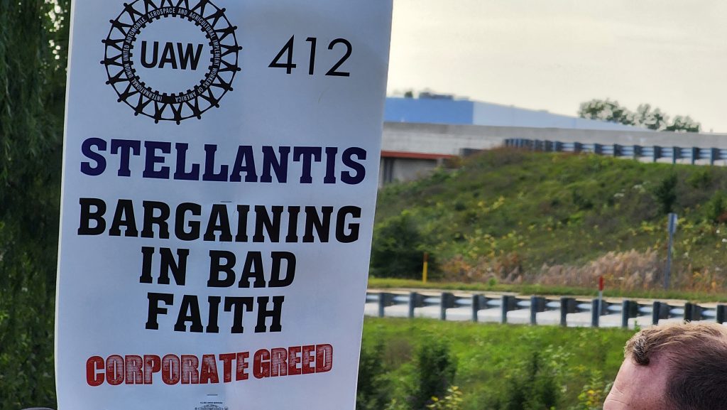 UAW union members hold up picket signs while on strike.