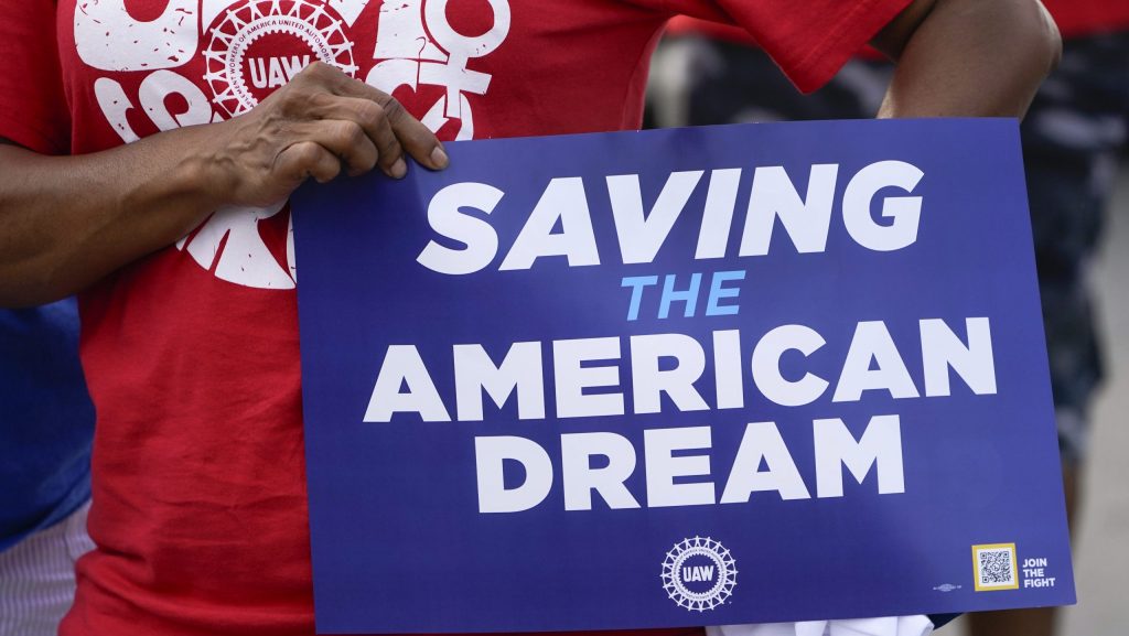 A United Auto Workers member holds a sign in the Labor Day parade in Detroit, Monday, Sept. 4, 2023. (AP Photo/Paul Sancya)