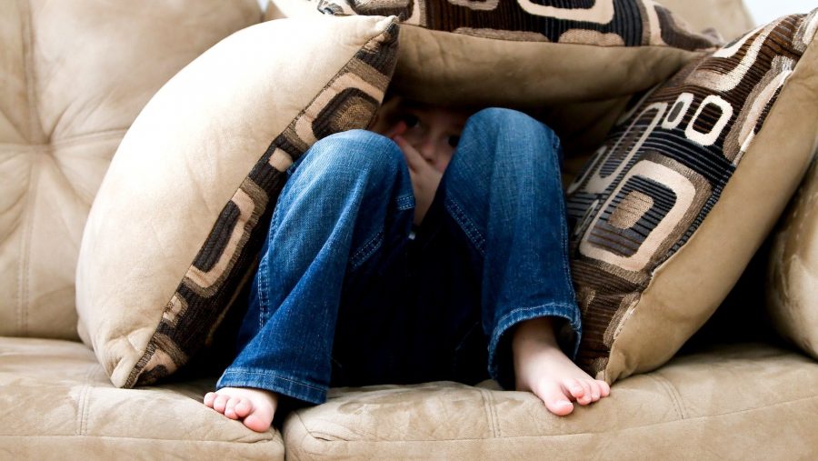Stock photo of a person hiding under pillows on a couch.