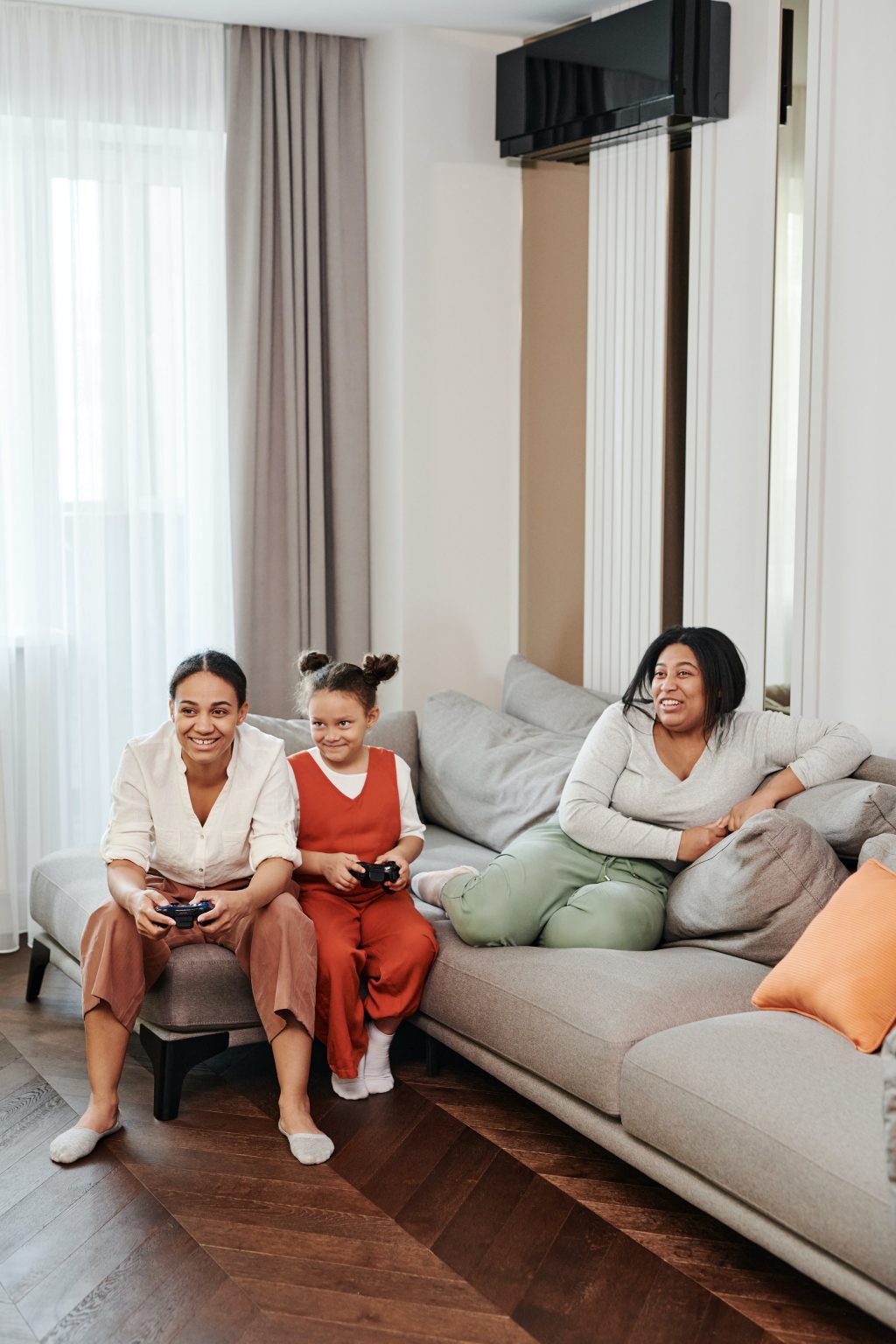 Three kids of different ages play a video game on the couch