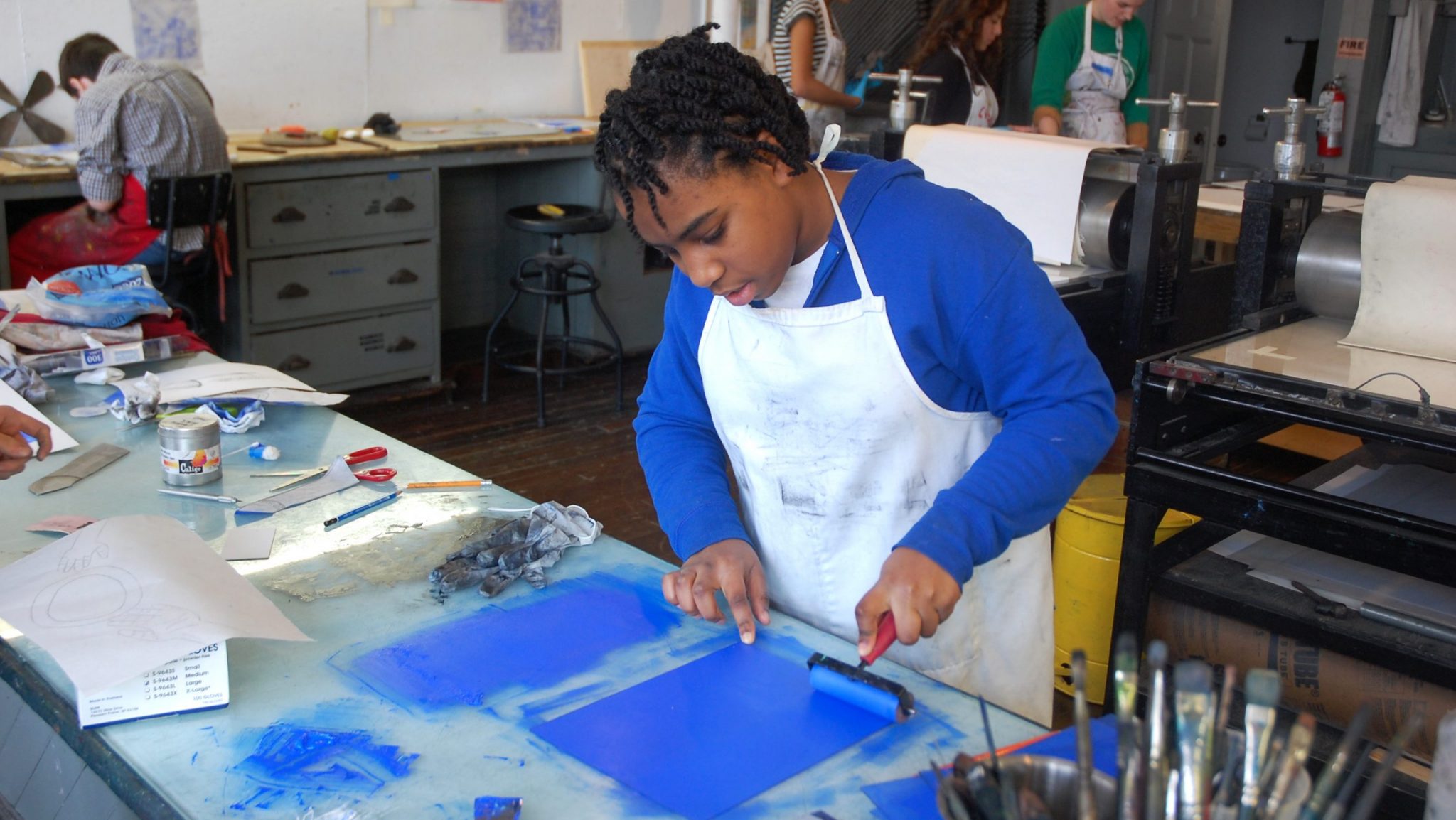 A young artist works on a block printing project in a studio.