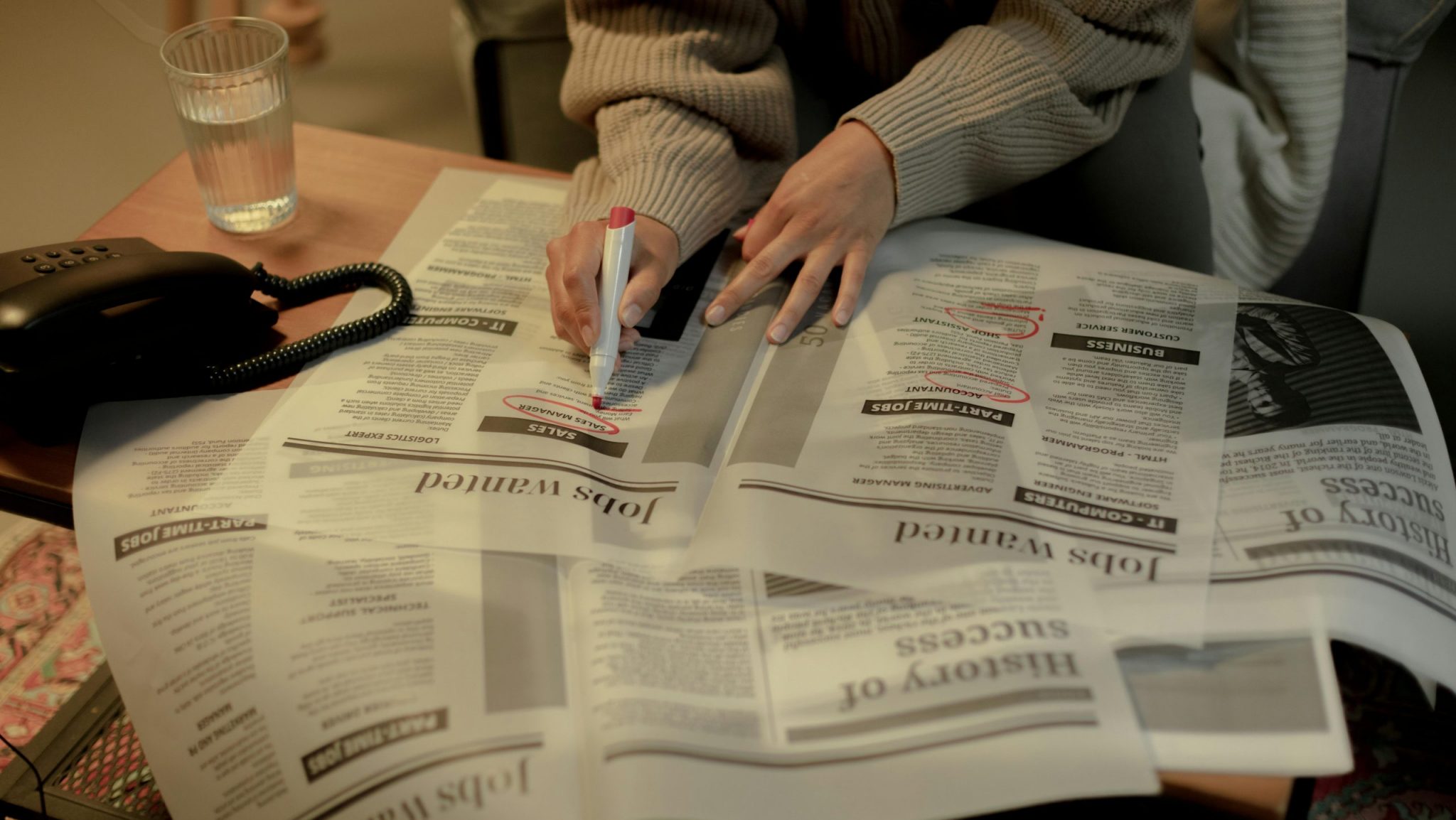 A woman circles job listings in the newspaper.