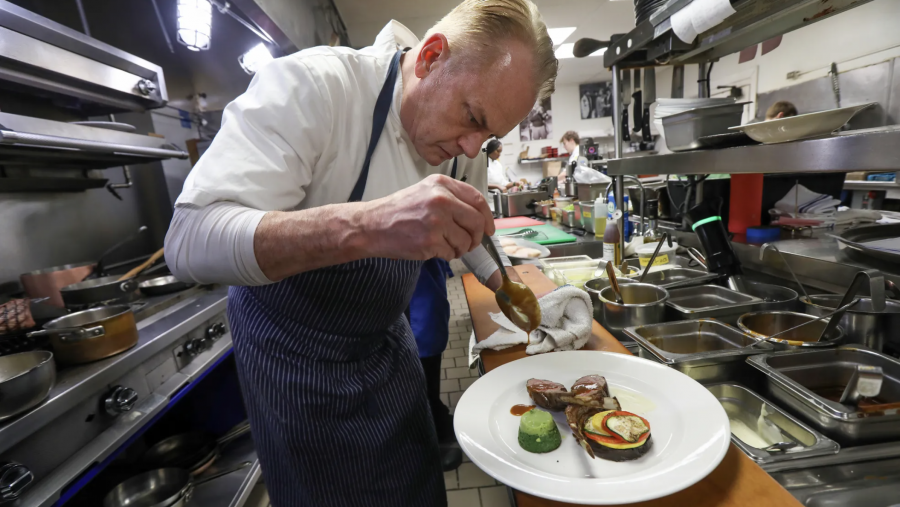 Chef and owner Paul Grosz dresses lamb chops with spinach custard and vegetables at Cuisine.