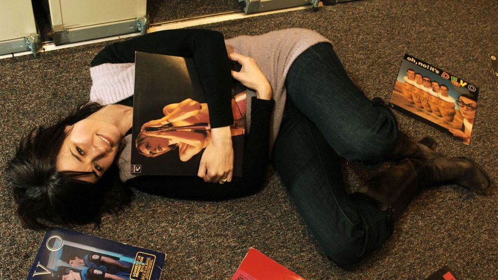 Liz Warner laying on the floor surrounded by vinyl records.